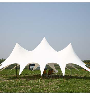 tente étoile avec trois mats posée dans un jardin